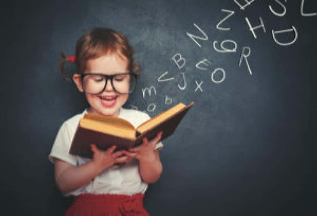 Young girl with glasses reading a red book.