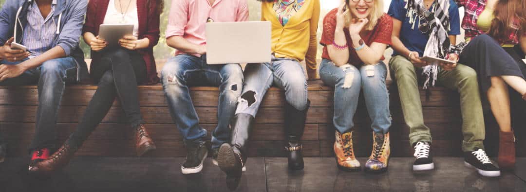 Seven people sitting down and holding various computers and tablets.