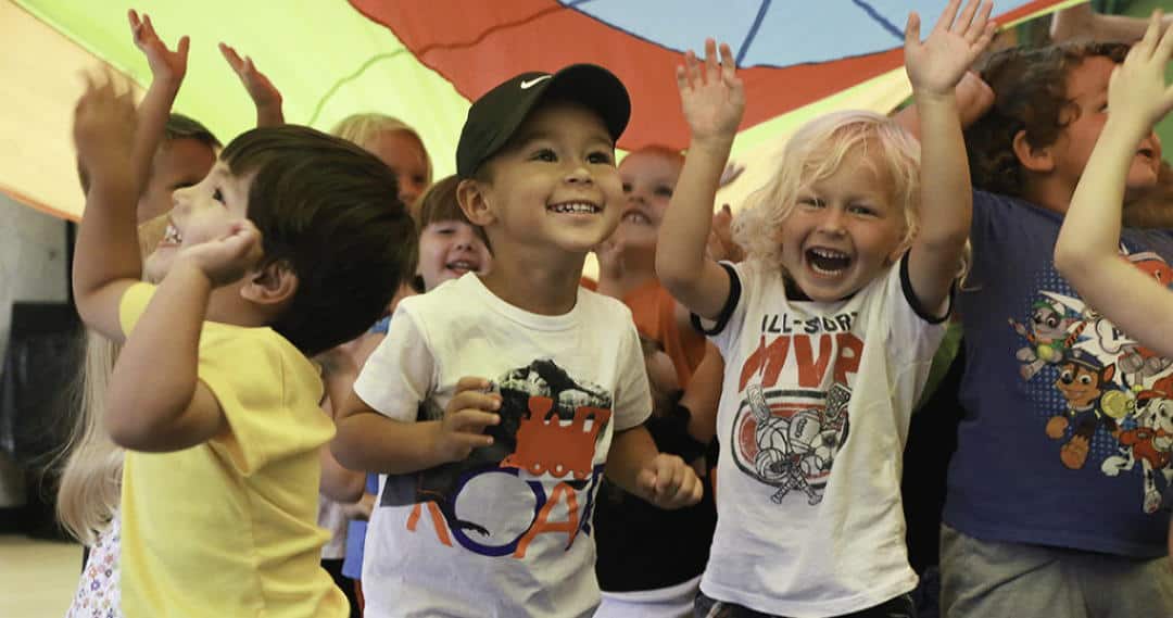 preschool kids playing with a parachute